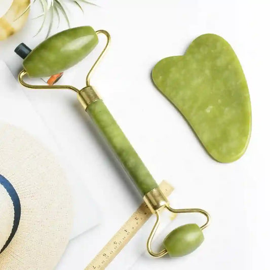 Green facial roller and gua sha tool on a white background