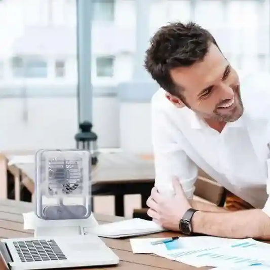 Man sitting at a desk with a laptop and documents, smiling.