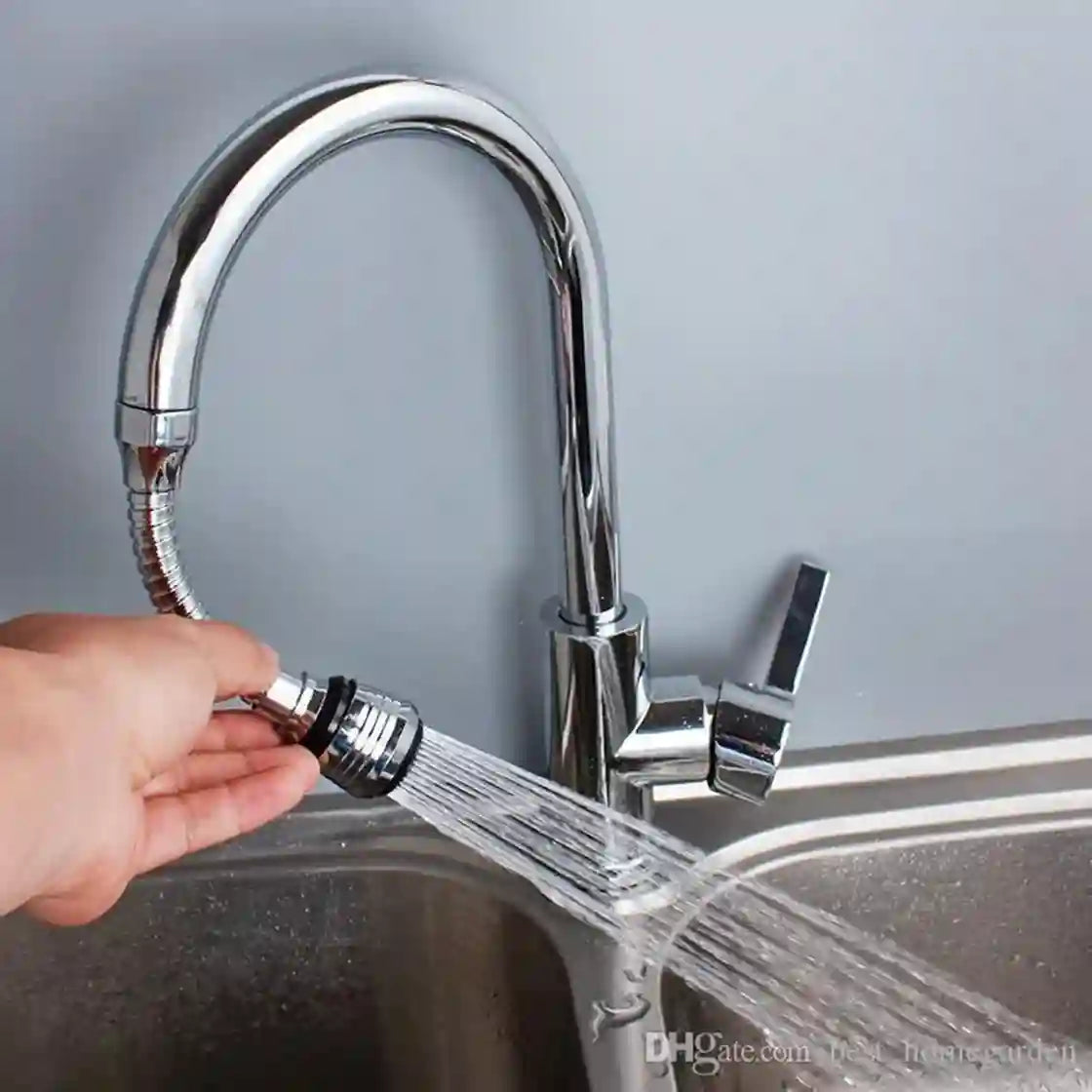 Chrome kitchen faucet with a hand holding a water filter attachment over a sink.