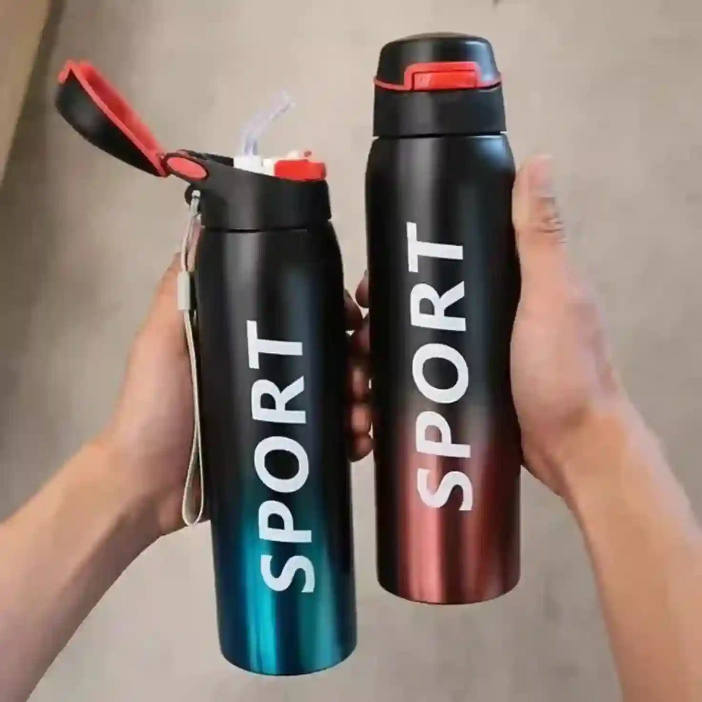 Two black 'SPORT' water bottles with red lids held by a person against a neutral background.