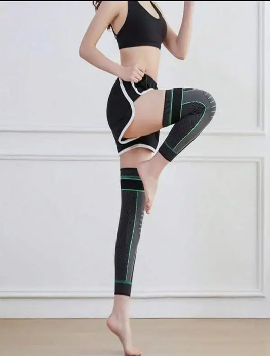 Person wearing black and green compression leggings with a white background