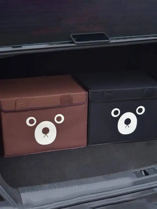 Two storage boxes with bear face designs in a car trunk.