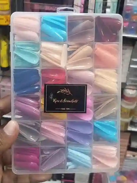 Set of colorful nail tips in a clear plastic case held by a hand.