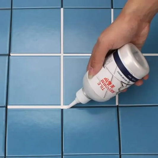 Person applying white adhesive from a bottle onto blue tiled floor