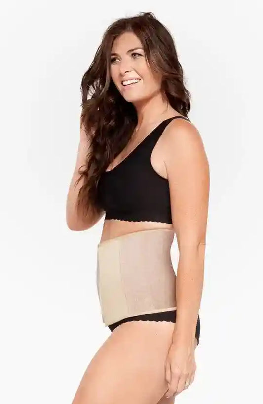 Woman wearing a black bra and beige shapewear on a white background