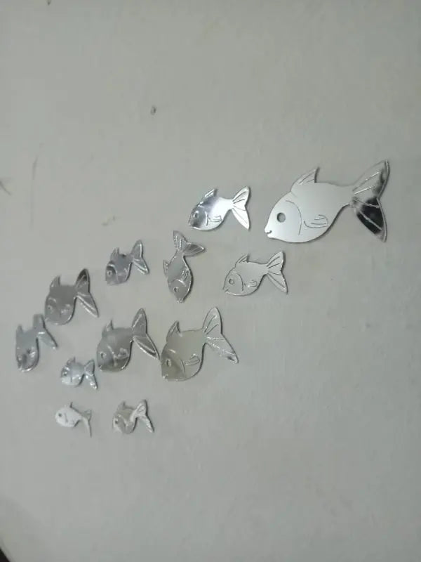Set of silver fish-shaped mirror stickers on a white background