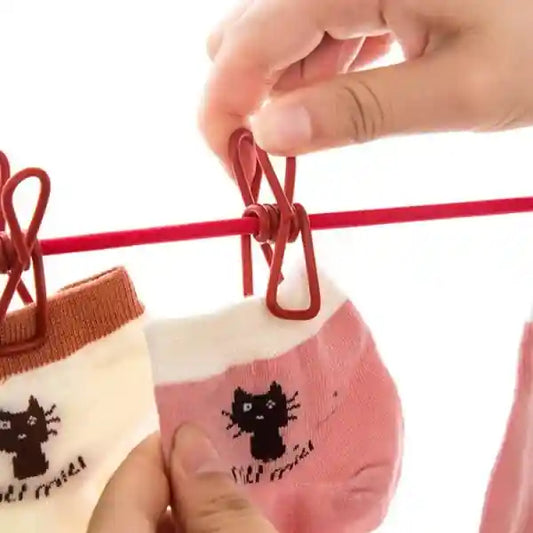 Person hanging pink socks with black cat designs on a red clothesline against a white background