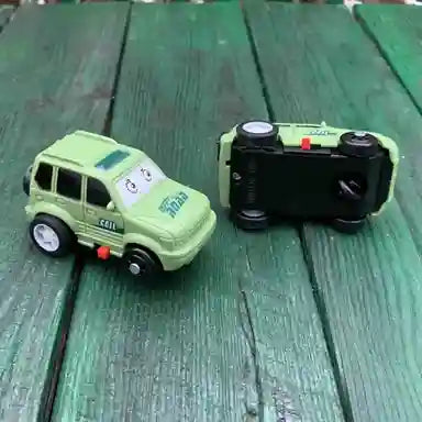 Two toy cars on a green wooden surface