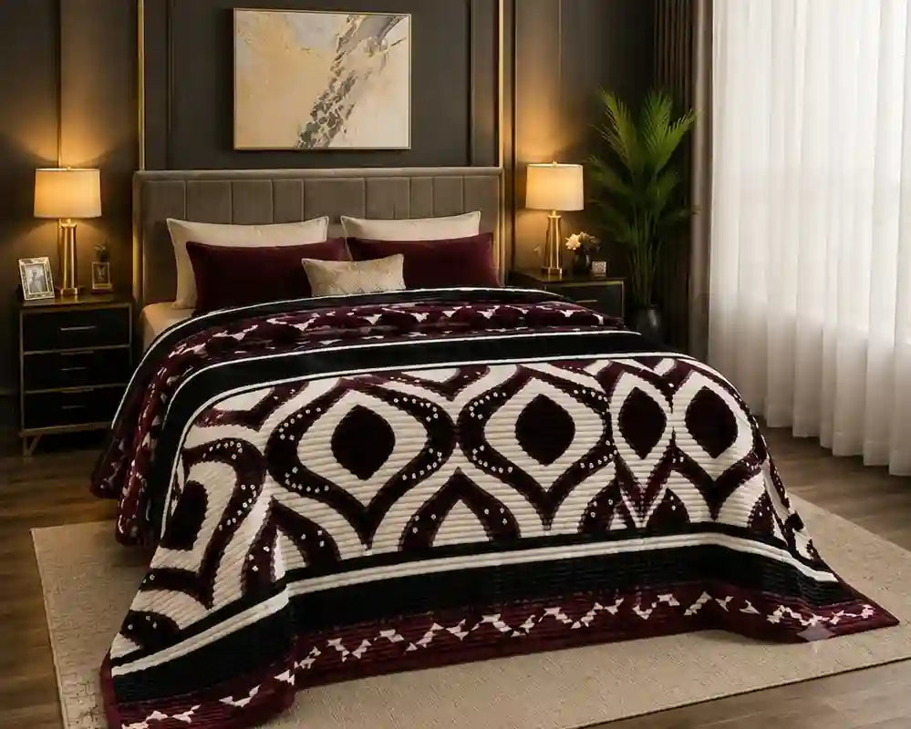 A bed dressed in a textured knit blanket featuring a bold geometric tribal pattern in burgundy, cream, and black, styled in a modern bedroom setting.