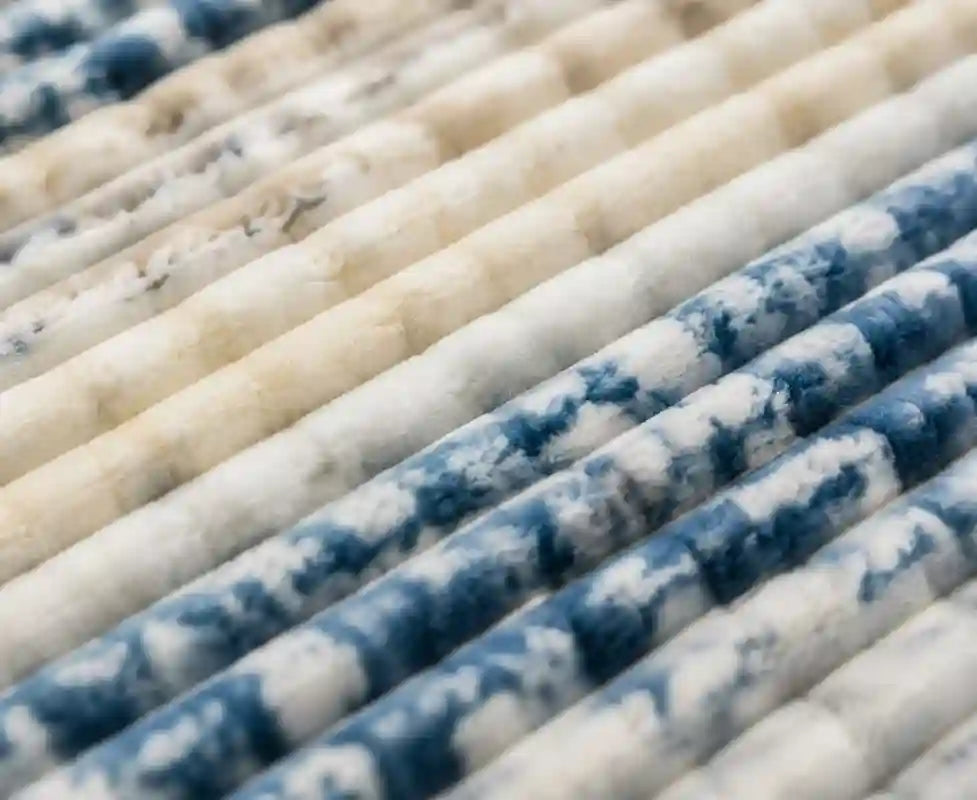 Close-up of pleated filter cartridges with alternating rows of off-white and blue marbled or mottled fabric or mesh tubes.