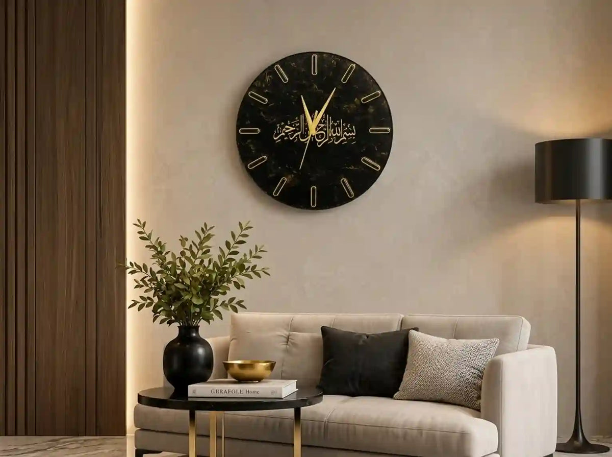 A round black wall clock with gold Arabic calligraphy hands and markers, mounted on a beige wall above a light beige sofa in a modern living room setting.