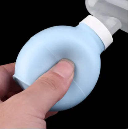 Hand holding a blue and white bulb syringe against a black background