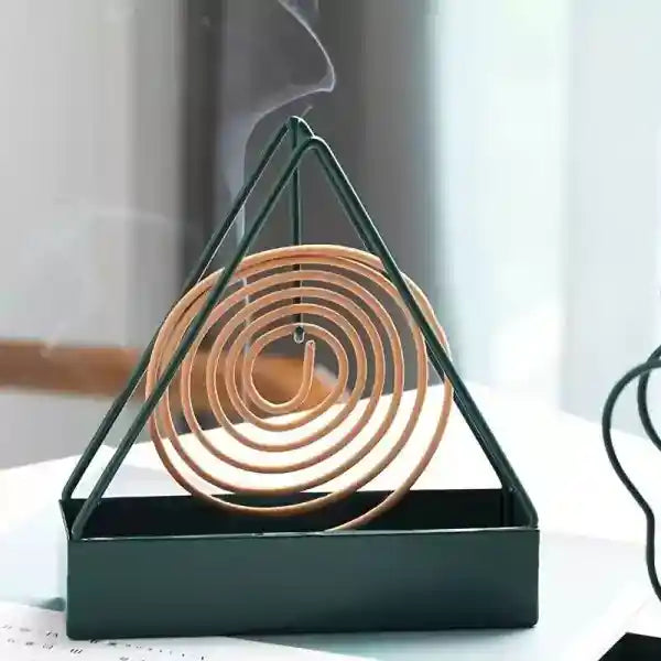 Triangular incense burner with wooden coils on a light background