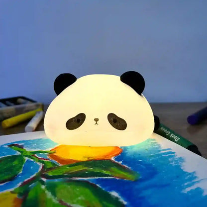 Panda-shaped night light on a painting with art supplies in the background