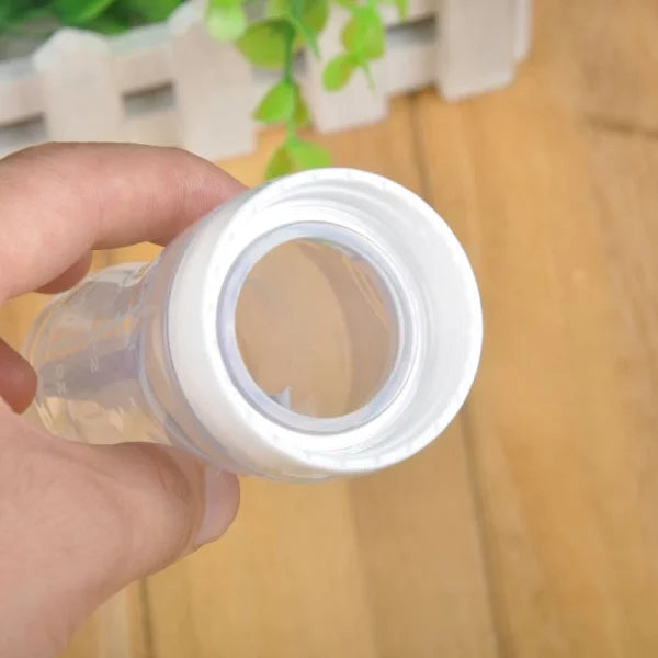 Hand holding a clear plastic container with a white lid against a blurred indoor background