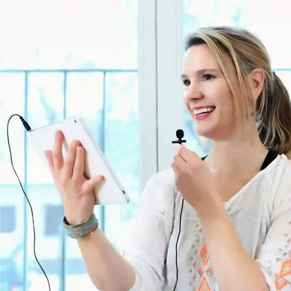 Woman holding a tablet with a microphone attached, smiling in front of a window.