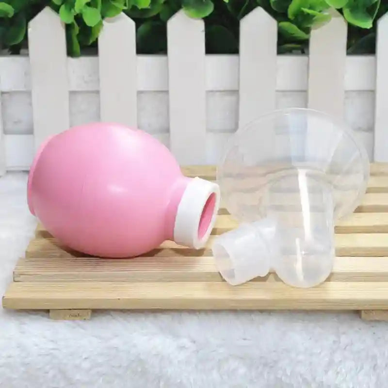 Pink and clear plastic devices on a wooden surface with a white picket fence and greenery in the background.
