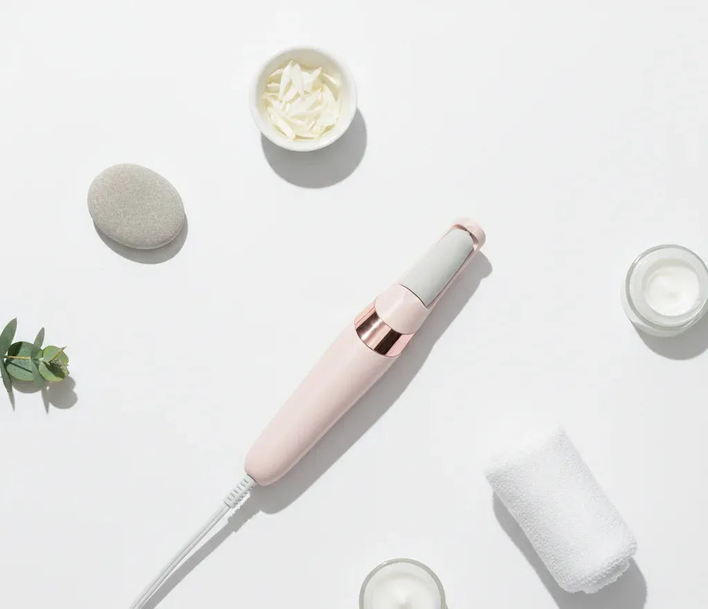 Pink handheld device on a white surface with cream containers and a plant.