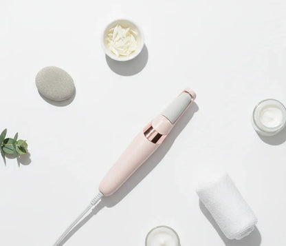 Pink handheld device on a white surface with cream containers and a plant.