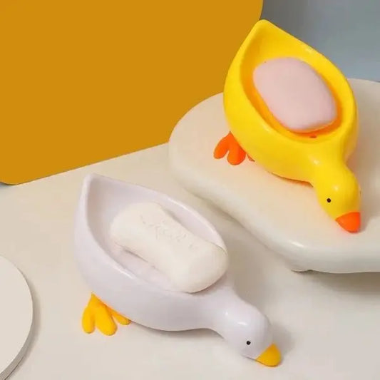 Two duck-shaped containers on a white surface with a yellow background