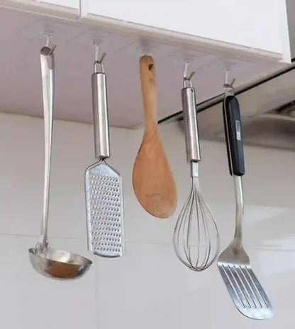 Set of kitchen utensils hanging under a cabinet including a ladle, grater, wooden spoon, whisk, and spatula.