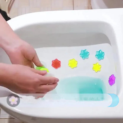 Colorful bath bombs being added to a bathtub with a child's hand.