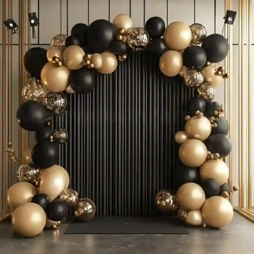 Balloon arch with black, gold, and silver balloons against a dark background