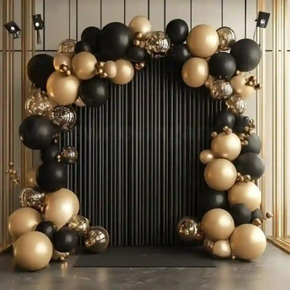 Balloon arch with black, gold, and silver balloons against a dark background