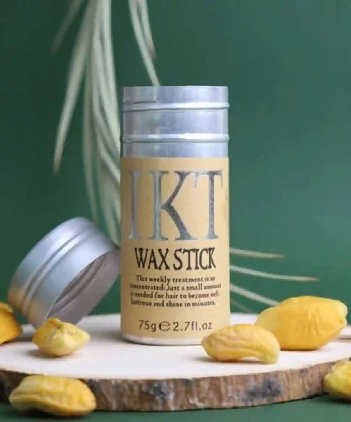 IKT Wax Stick with packaging on a wooden block against a green background