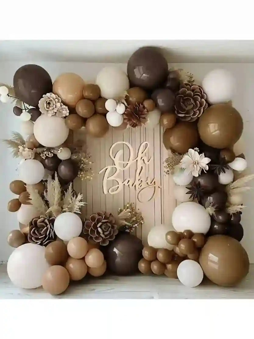 Balloon arch with brown, beige, and white balloons, flowers, and cones with 'Oh Baby!' sign.