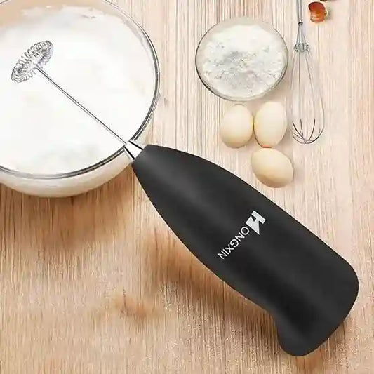Black milk frother with 'TONGNAN' branding on a wooden surface with eggs and a bowl.