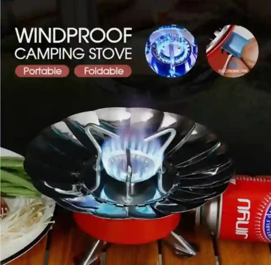 Windproof camping stove with blue flame, surrounded by ingredients and a canister on a dark background.