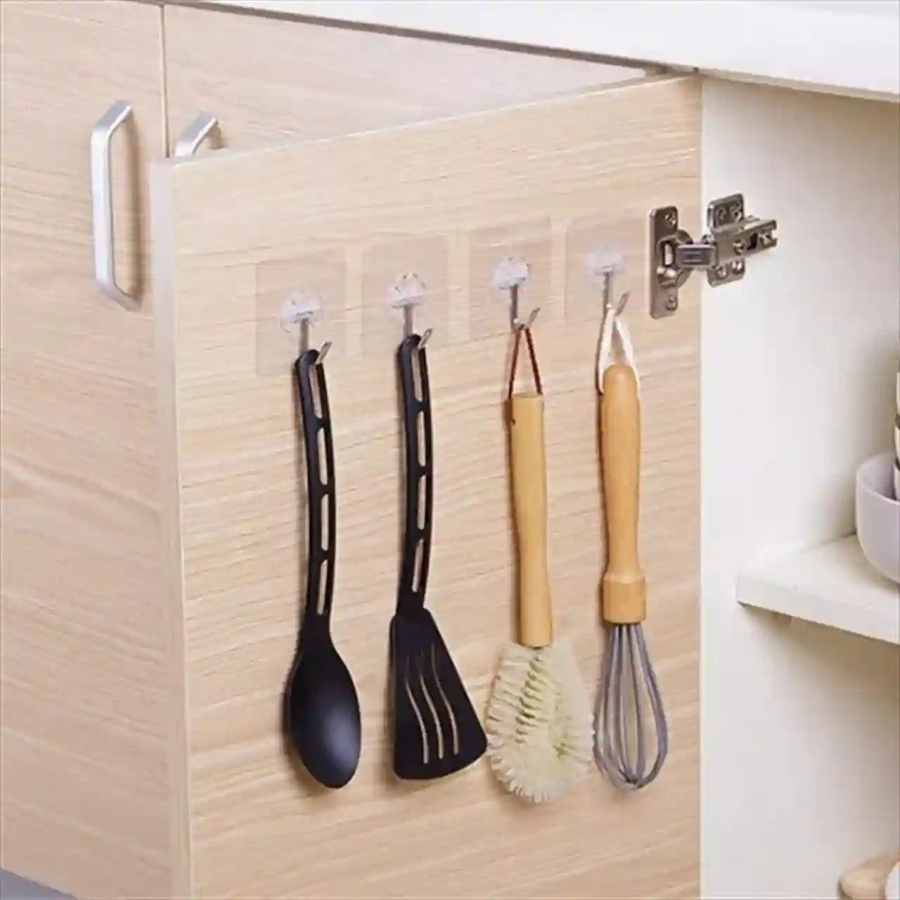 Kitchen utensils hanging on clear hooks attached to a cabinet door.