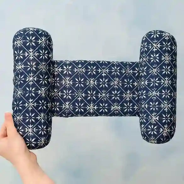Navy blue pillow with white geometric pattern held by a hand against a light blue background
