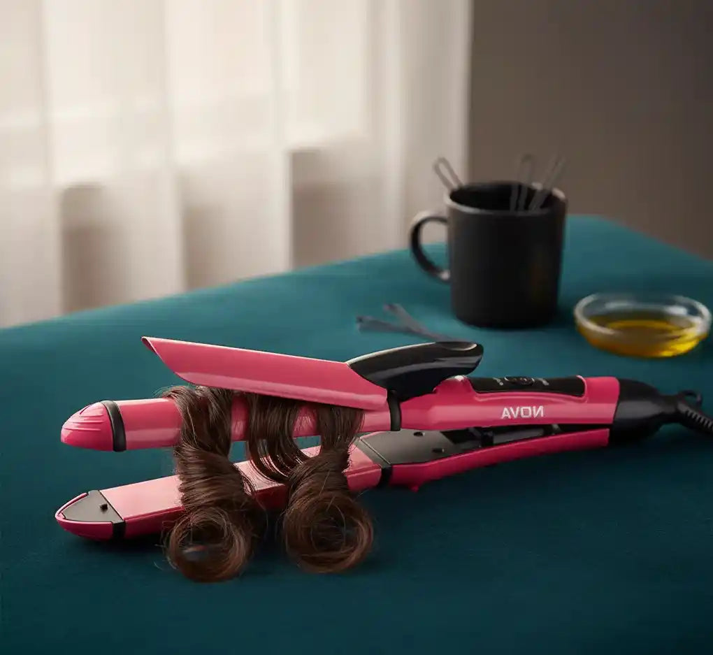Pink hair straightener with hair on a blue surface, with a cup and utensils in the background.