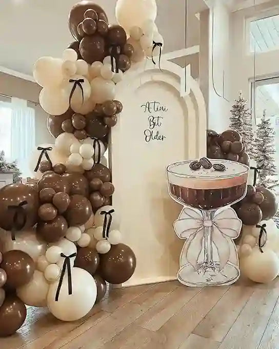 Decorative balloon arch with a cake stand and 'Actuálé, çété plus élégante' sign in a room.