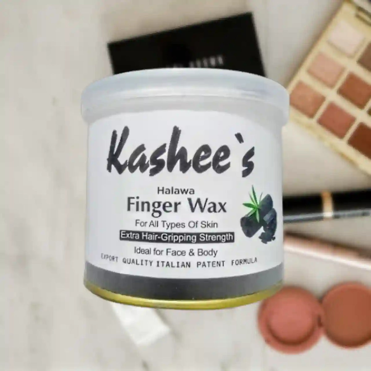 A jar of Kashee's Halawa Finger Wax, a hair grip strengthening product, displayed on a light marble surface with cosmetic items in the background.