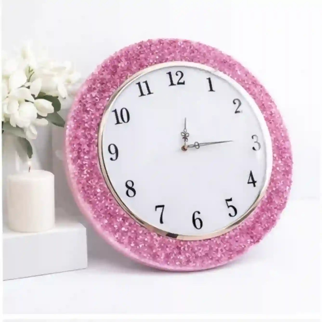 Pink glittery wall clock on a white background