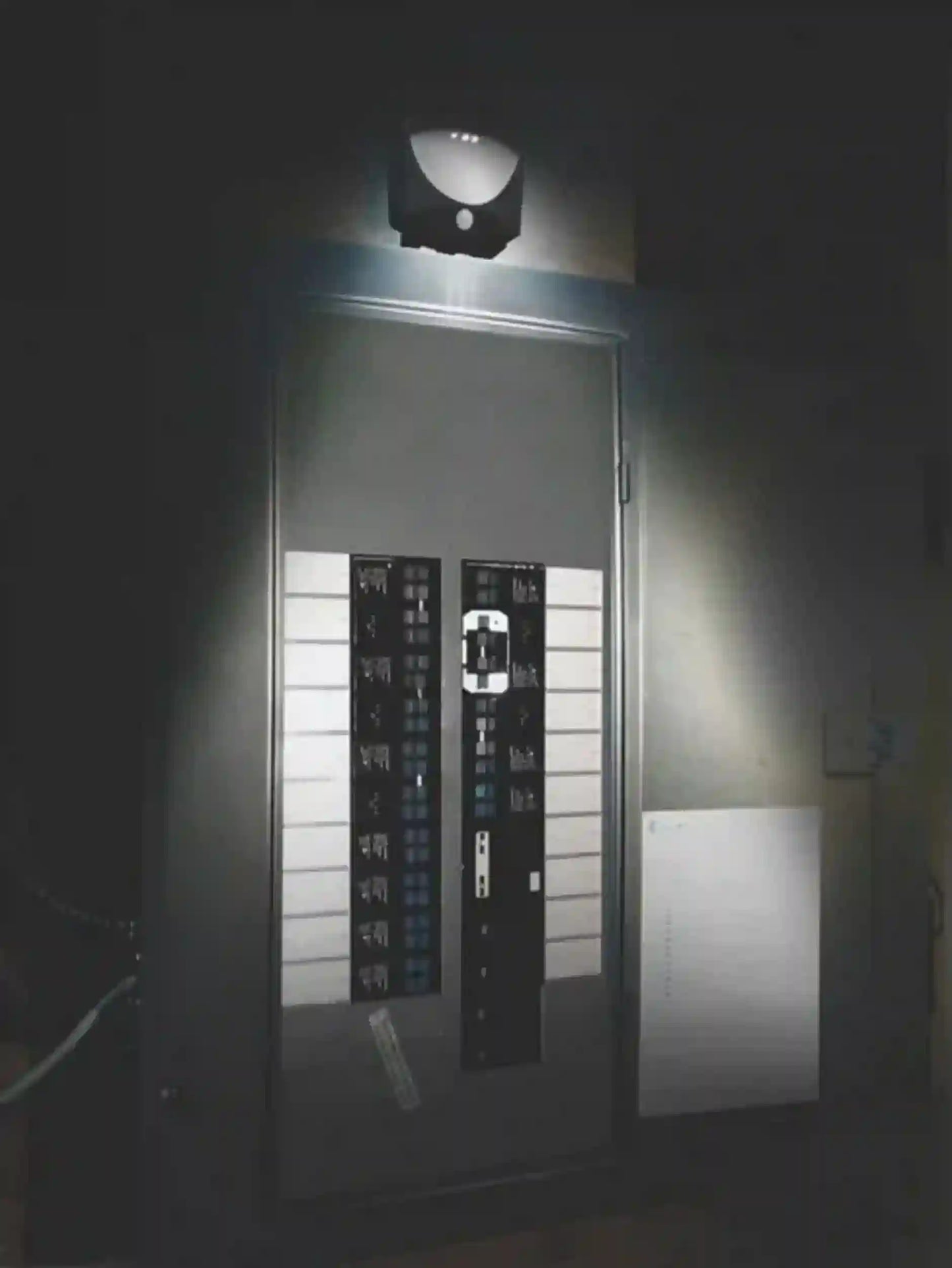 Security camera mounted on a wall with a light shining on it, in a dark setting.