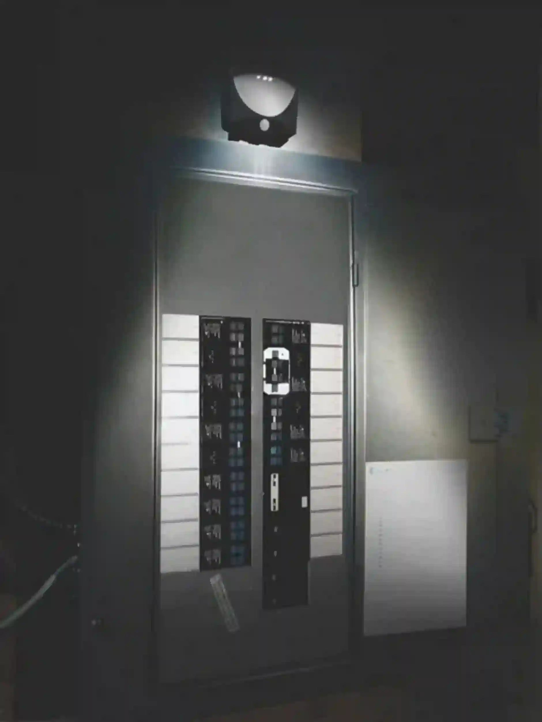 Security camera mounted on a wall with a light shining on it, in a dark setting.