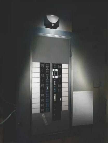 Security camera mounted on a wall with a light shining on it, in a dark setting.