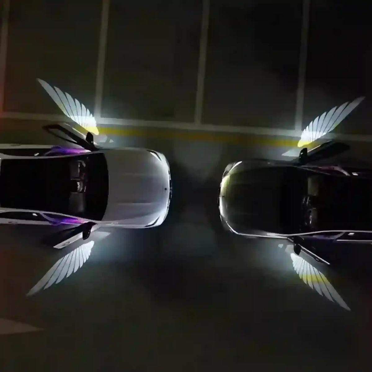 Two cars with angel wing designs on a dark floor.