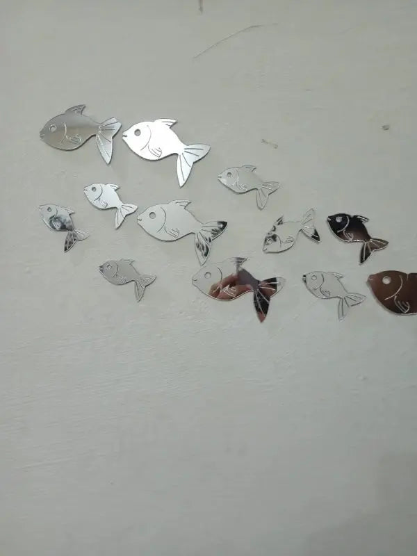 Fish-shaped mirror stickers on a white wall