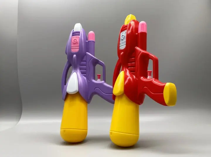 Two colorful toy water guns, one purple and yellow, one red and yellow, on a gray background.