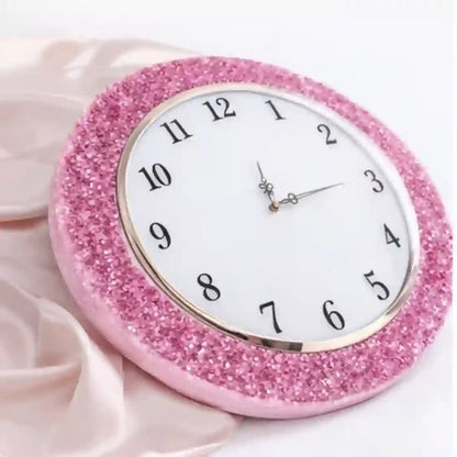 Pink glittery clock on a light pink fabric background