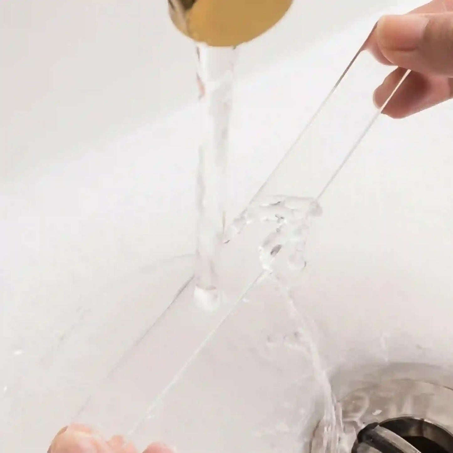 Clear plastic bag with a gold handle being held over a sink.
