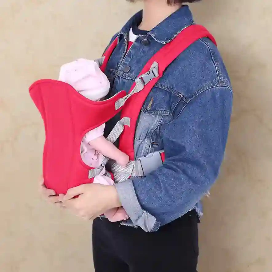 Person holding a baby in a red and gray baby carrier against a beige background