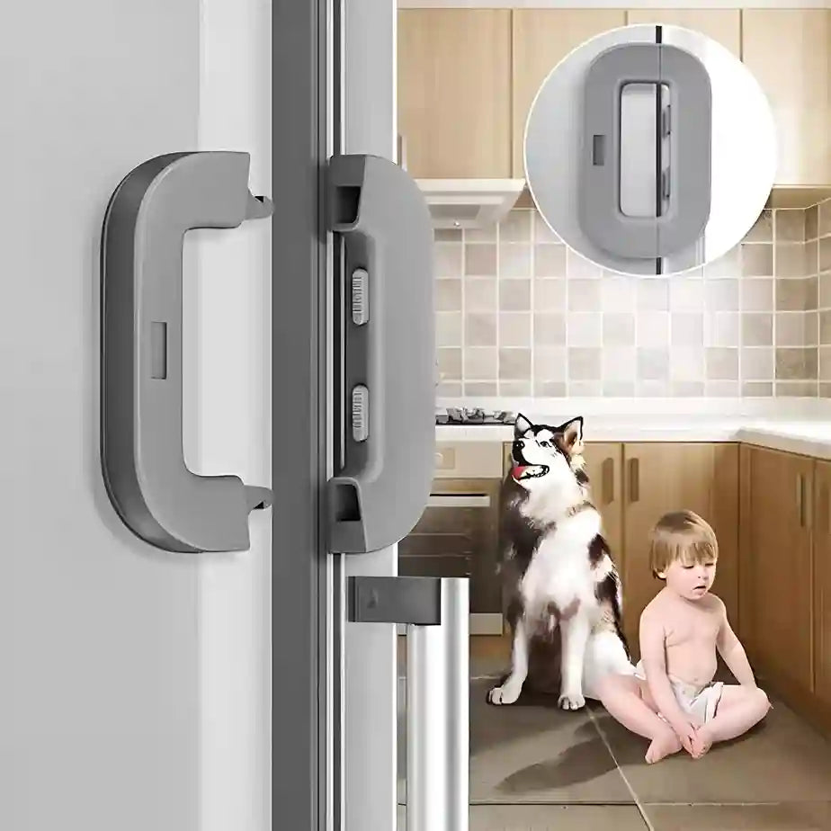 Child and dog sitting on the floor next to a glass door with a lock mechanism, kitchen setting.