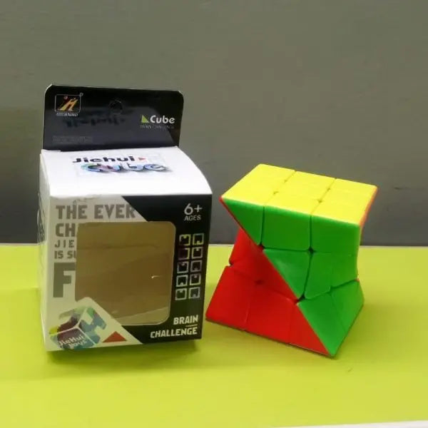 Colorful twisted Rubik's Cube next to its packaging on a green surface with a gray background