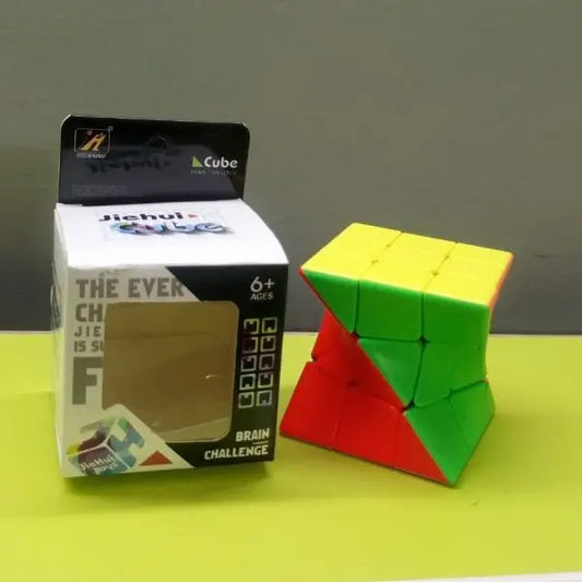 Colorful twisted Rubik's Cube next to its packaging on a green surface with a gray background